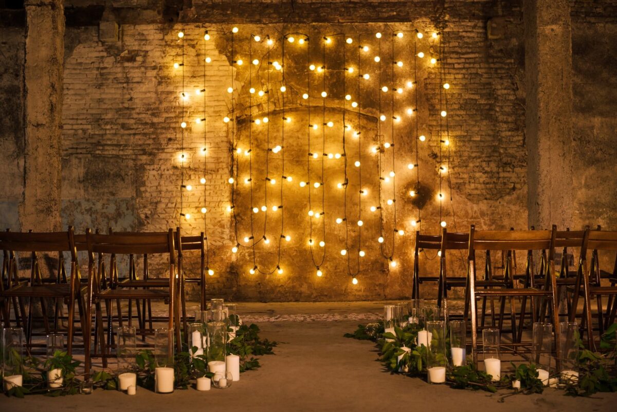 Curtain lights hung in straight rows as a glowing backdrop behind a wedding ceremony arch