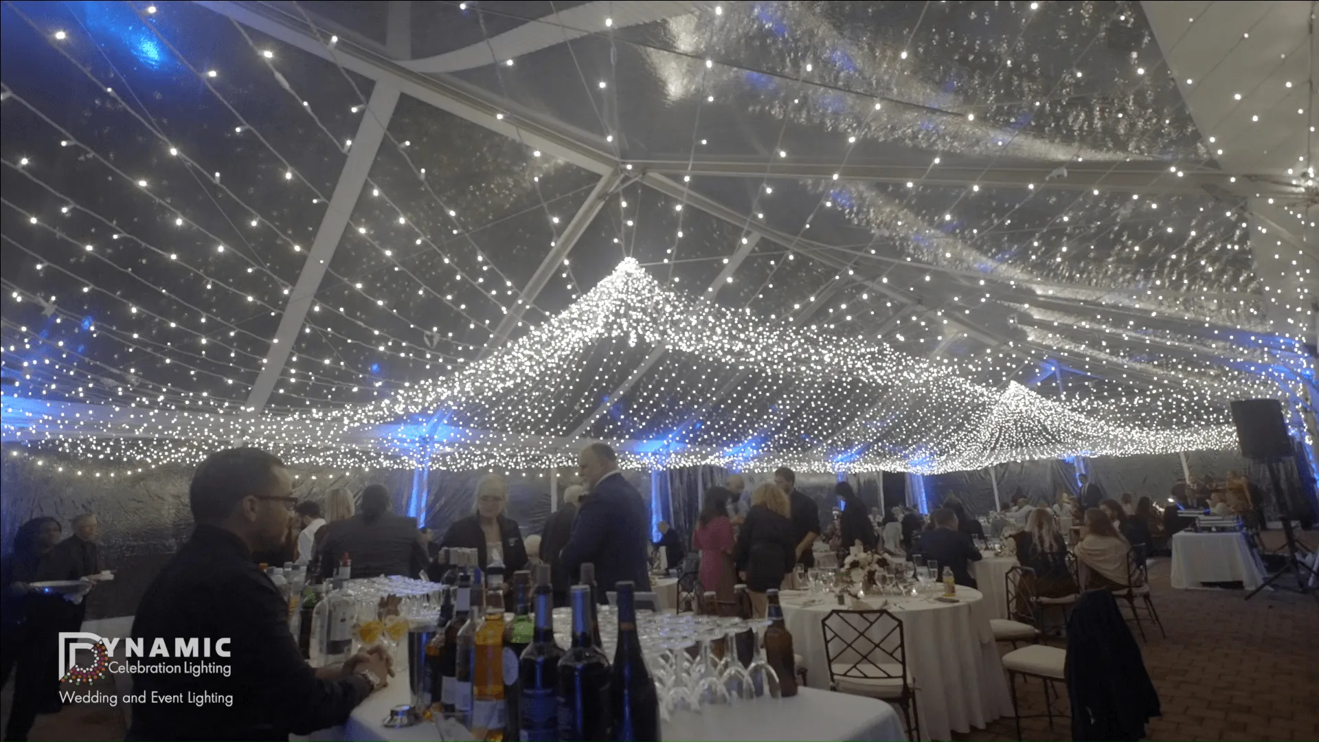 A string light canopy suspended overhead creating a glowing ceiling at a wedding